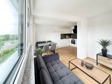 Lichtdurchfluteter Wohnbereich mit Zugang zur Küche, Essplatz und Blick auf das angrenzende grüne Wohnumfeld – ideal für Familien und Paare.