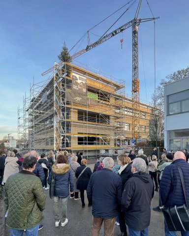 Zahlreiche Gäste versammeln sich beim Richtfest vor dem eingerüsteten Schulzentrum Bönnigheim während der Bauphase