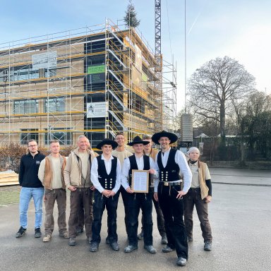 Zimmererteam und Projektbeteiligte beim Richtfest vor dem erweiterten Schulzentrum Bönnigheim in Holzbauweise.