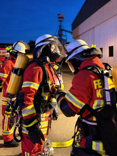 Feuerwehrleute mit Atemschutz bereiten sich auf den Einsatz bei der Übung auf dem Gelände von Bauer Holzbau vor.