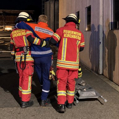 Zwei Feuerwehrleute der Feuerwehr Kirchberg begleiten einen Statisten der Jugendfeuerwehr Satteldorf bei der Personenrettung.