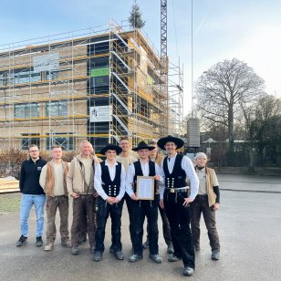 Zimmererteam und Projektbeteiligte beim Richtfest vor dem erweiterten Schulzentrum Bönnigheim in Holzbauweise.